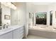 Bright bathroom with a soaking tub under a decorative window and a large vanity at 44434 N 20Th St, New River, AZ 85087