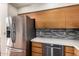 Kitchen features stainless steel refrigerator, natural wood cabinetry, mosaic backsplash, and stone countertops at 44434 N 20Th St, New River, AZ 85087