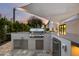 Close up of outdoor kitchen with stainless steel grill, storage, sink, and marble countertops at 4748 E Redfield Rd, Phoenix, AZ 85032