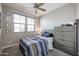 Inviting bedroom features a ceiling fan, window with blinds, and a dresser for storage at 7735 W Agora Ln, Phoenix, AZ 85043