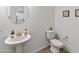 Stylish powder room with pedestal sink, round mirror and decorative wall art, exuding modern elegance at 8804 W Vista Ave, Glendale, AZ 85305