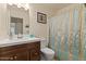 This well-lit bathroom features a vanity with a sink, a toilet, and a shower with a curtain at 9826 E Irwin Cir, Mesa, AZ 85209