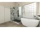 Modern bathroom featuring a soaking tub, marble shower, and glass block window at 10318 E Irwin Ave, Mesa, AZ 85209