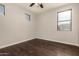 Empty bedroom with wood-look floors, a ceiling fan, and multiple windows providing ample lighting at 10318 E Irwin Ave, Mesa, AZ 85209