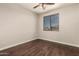 Empty bedroom with wood-look floors, a ceiling fan, and a large window providing natural lighting at 10318 E Irwin Ave, Mesa, AZ 85209