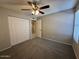 This carpeted bedroom features a ceiling fan and a closet with white doors at 113 W Bluefield Ave, Phoenix, AZ 85023