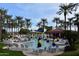 Community pool area surrounded by palm trees, lounge chairs, and shade umbrellas at 15109 W Camino Estrella Dr, Surprise, AZ 85374