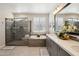 Bathroom with gray cabinets, double sinks, tub and glass shower at 16949 W La Reata Ave, Goodyear, AZ 85395