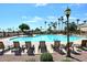 Inviting community pool area featuring lounge chairs, clear water, and swaying palm trees in the background at 16949 W La Reata Ave, Goodyear, AZ 85395