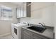 Functional laundry room with modern washer, dryer and gray countertop with stainless sink at 16949 W La Reata Ave, Goodyear, AZ 85395