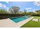 Backyard swimming pool with lounge chairs, mature trees, and blue sky at 16949 W La Reata Ave, Goodyear, AZ 85395