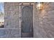 Close up of decorative metal front door with stone surround and an ornate wall lantern at 20709 N 59Th Dr, Glendale, AZ 85308