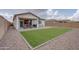 Spacious backyard featuring artificial grass, gravel landscaping, and patio with seating at 40520 W Haley Dr, Maricopa, AZ 85138