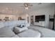 Open living room with a large sectional sofa, ceiling fan, and view into the kitchen and dining area at 40520 W Haley Dr, Maricopa, AZ 85138