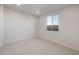 Bright bedroom featuring neutral carpet, white walls, a large window, and ample natural light at 42850 W Palo Abeto Dr, Maricopa, AZ 85138