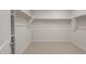 Spacious walk-in closet featuring neutral carpet flooring and white shelving for optimal storage at 42850 W Palo Abeto Dr, Maricopa, AZ 85138