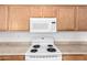 Close-up shot of the kitchen stove, microwave, and upper wood cabinets at 44792 W Paitilla Ln, Maricopa, AZ 85139