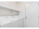Functional laundry room with a white washer and dryer set and a convenient shelf at 44792 W Paitilla Ln, Maricopa, AZ 85139