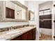 Well-lit bathroom featuring double sinks with granite countertops and tiled shower at 5323 W Rose Garden Ln, Glendale, AZ 85308