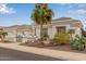 Charming white home featuring a desert landscape, mature palm trees, and a three-car garage at 5323 W Rose Garden Ln, Glendale, AZ 85308