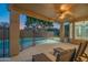 Covered patio with lounge seating overlooks the fenced pool and lush landscaping at 7415 W Via De Luna Dr, Glendale, AZ 85310
