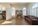 Bright living room featuring built-in bookshelves, arched windows, plantation shutters and a brown leather sofa at 7415 W Via De Luna Dr, Glendale, AZ 85310