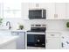 Well-lit kitchen featuring stainless steel oven, microwave, white cabinets, and a tile backsplash at 909 E Desert Ln, Phoenix, AZ 85042