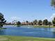 Scenic pond view, featuring a fountain, waterfront homes, and blue skies and palm trees at 10914 E Navajo Dr, Sun Lakes, AZ 85248