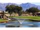 Scenic pond with fountain on a golf course, featuring lush landscaping and mountain views at 11408 E Natal Ave, Mesa, AZ 85209