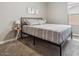 Neutral bedroom with a bed that has a metal frame, matching bedding, and a small side table next to a window at 1158 E Harvard Ave, Gilbert, AZ 85234