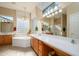 Luxurious bathroom with dual vanities, a soaking tub, and a large window at 16935 W Desert Blossom Way, Surprise, AZ 85387