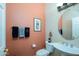 Charming powder room with stylish round mirror, unique artwork, and a pedestal sink at 16935 W Desert Blossom Way, Surprise, AZ 85387
