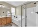 Bright bathroom featuring a shower, soaking tub, and a vanity with wooden cabinetry at 18298 N Kari Ln, Maricopa, AZ 85139