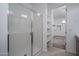 Bathroom with walk-in shower and view into walk-in closet with shelves at 21291 W Edgemont Ave, Buckeye, AZ 85396