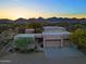 Expansive southwestern home with a multi-car garage and desert landscaping against a mountainous sunset backdrop at 39424 N Spur Cross Rd, Cave Creek, AZ 85331