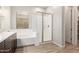 Bright bathroom featuring a glass-enclosed shower, soaking tub, and modern wood-look flooring at 41262 W Almira Dr, Maricopa, AZ 85138