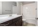 Modern bathroom with dark wood vanity and matching framed mirror and tub-shower combo at 41262 W Almira Dr, Maricopa, AZ 85138