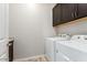 Well-equipped laundry room with front-load washer and dryer and dark cabinetry at 41262 W Almira Dr, Maricopa, AZ 85138