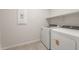 A laundry room with modern washer and dryer units, tile floors, and built-in shelving at 42860 W Palo Abeto Dr, Maricopa, AZ 85138
