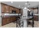 Kitchen island with granite countertop, pendant lighting, and dark wood cabinets at 5054 S Advant Ter, Mesa, AZ 85212