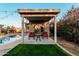Poolside cabana with red chairs provides a shady spot to relax and enjoy the backyard with grass at 5641 E Aster Dr, Scottsdale, AZ 85254