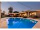 Backyard view with a sparkling in-ground pool, with covered patio, outdoor kitchen, and ambient string lights at 5641 E Aster Dr, Scottsdale, AZ 85254
