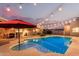 Gorgeous backyard pool with Baja step, umbrella table and outdoor kitchen and bar area under festive string lights at 5641 E Aster Dr, Scottsdale, AZ 85254