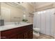 Well-lit bathroom featuring a dark wood vanity, white marble countertop and patterned shower curtain at 926 W Grand Caymen Dr, Gilbert, AZ 85233