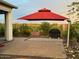 Outdoor patio with pavers, lush landscaping, and a large red umbrella at 12035 W Roy Rogers Rd, Peoria, AZ 85383