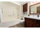 This bathroom features a shower and tub combination, dark wood vanity, and decorative mirror at 18442 N 104Th Ave, Sun City, AZ 85373