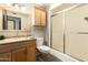 Bathroom with wooden vanity and mirror, shower with sliding glass door, and overhead storage at 18442 N 104Th Ave, Sun City, AZ 85373
