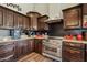 Open-concept kitchen featuring stainless steel range, dark cabinetry, granite countertops, and black backsplash at 19612 W Georgia Ave, Litchfield Park, AZ 85340