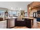 Spacious kitchen island with stainless steel sink, granite countertop, dark wood cabinets, and brick accent wall at 19612 W Georgia Ave, Litchfield Park, AZ 85340