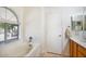Bright bathroom features large soaking tub with window, vanity and separate door at 20218 N 61St Ave, Glendale, AZ 85308